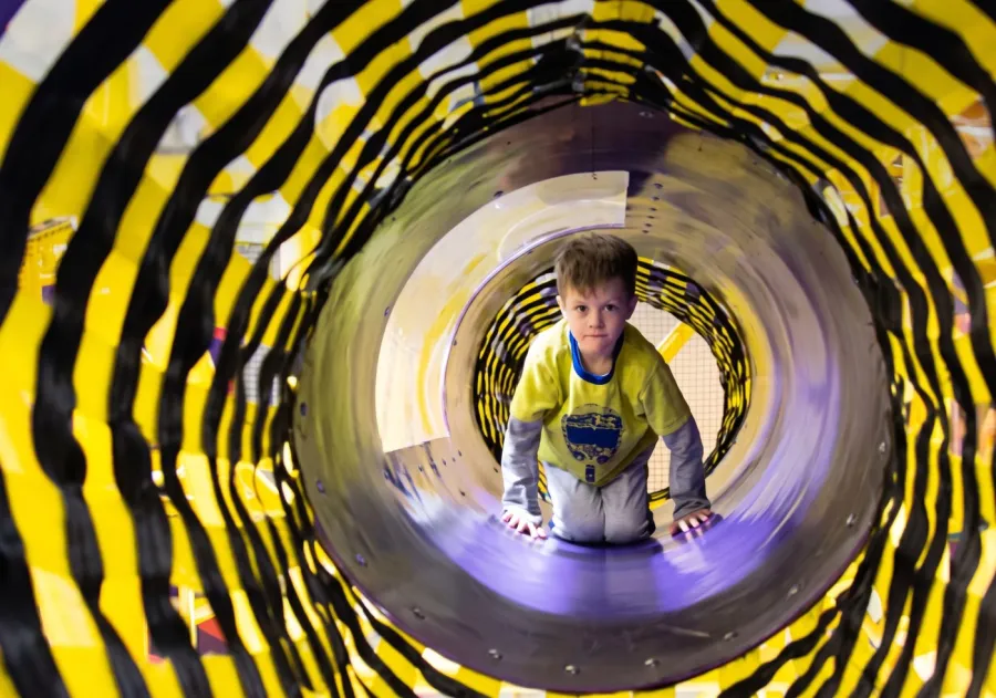Túnel tobogán de juegos infantiles con niño jugando